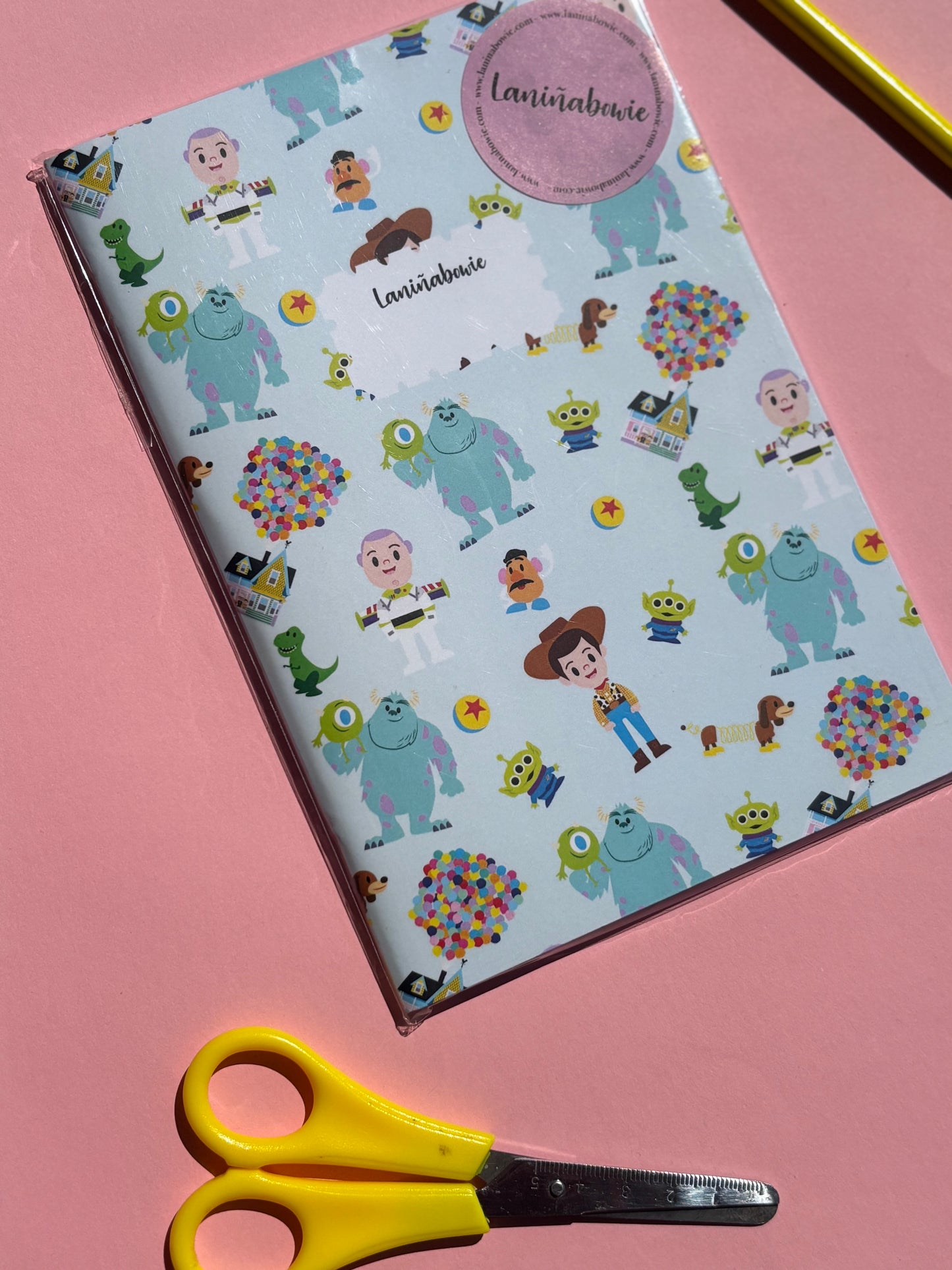 Libreta de tapa blanda con estampado de personajes de Pixar como Woody, Sulley, la casa de Up y más. El diseño es de la marca laniñabowie.