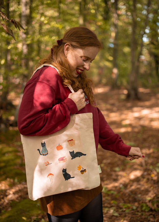Tote bag de la colección de Orange passport & laniñabowie para este otoño 2025. Diseños exclusivos inspirados en los atardeceres anaranjados de esta época del año con ilustraciones de Bolita el adorable gato de Orang Passport y diferentes elementos característicos del otoño. esta tote bag es de algodón orgánico y perfecta para tus tardes en ka cafetería, de visita a tu librería favorita o para llevar en tu día a día.