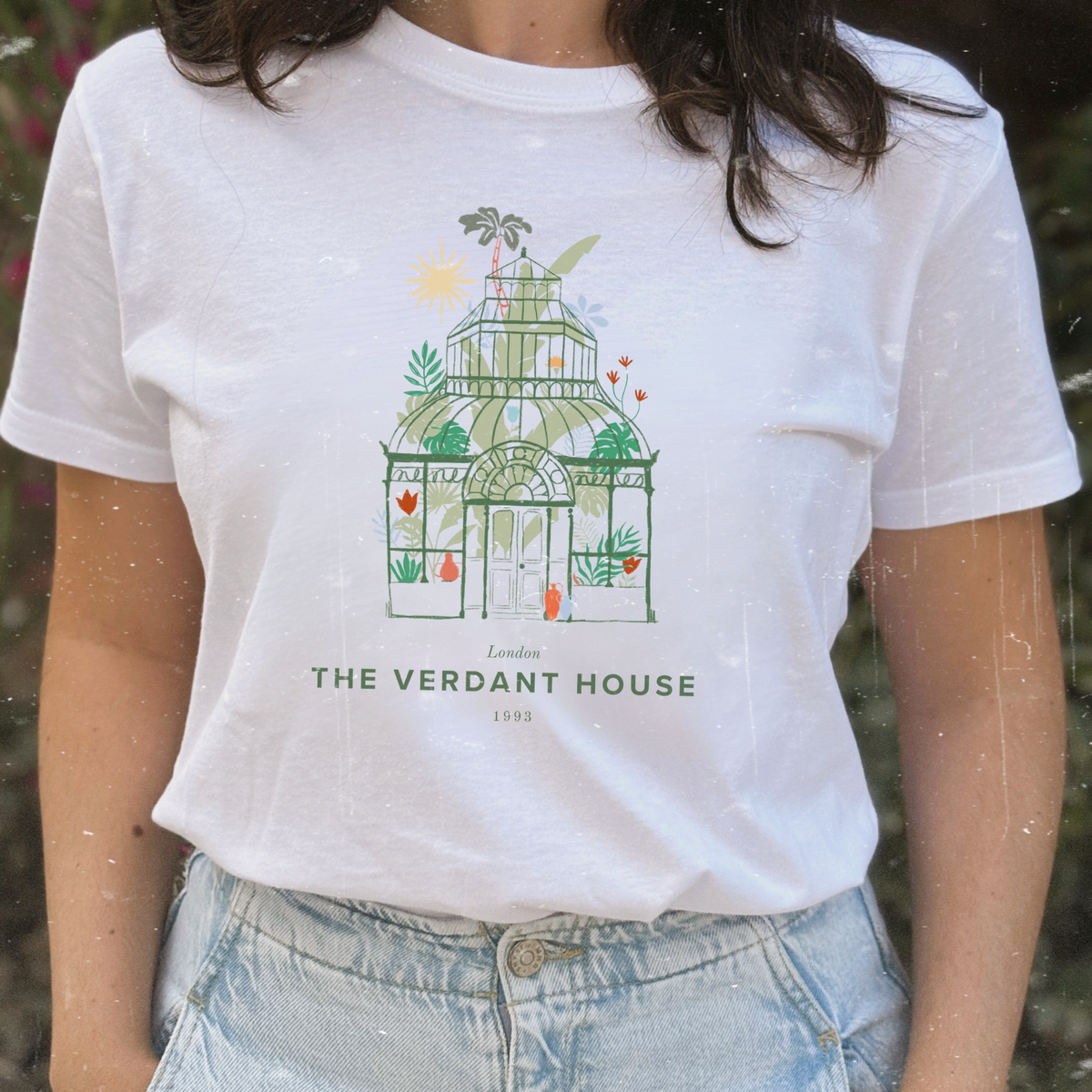 Camiseta blanca de Laniñabowie modelo Plant lover con ilustración de un invernadero con plantas y el texto “The Verdant House”, vista de frente