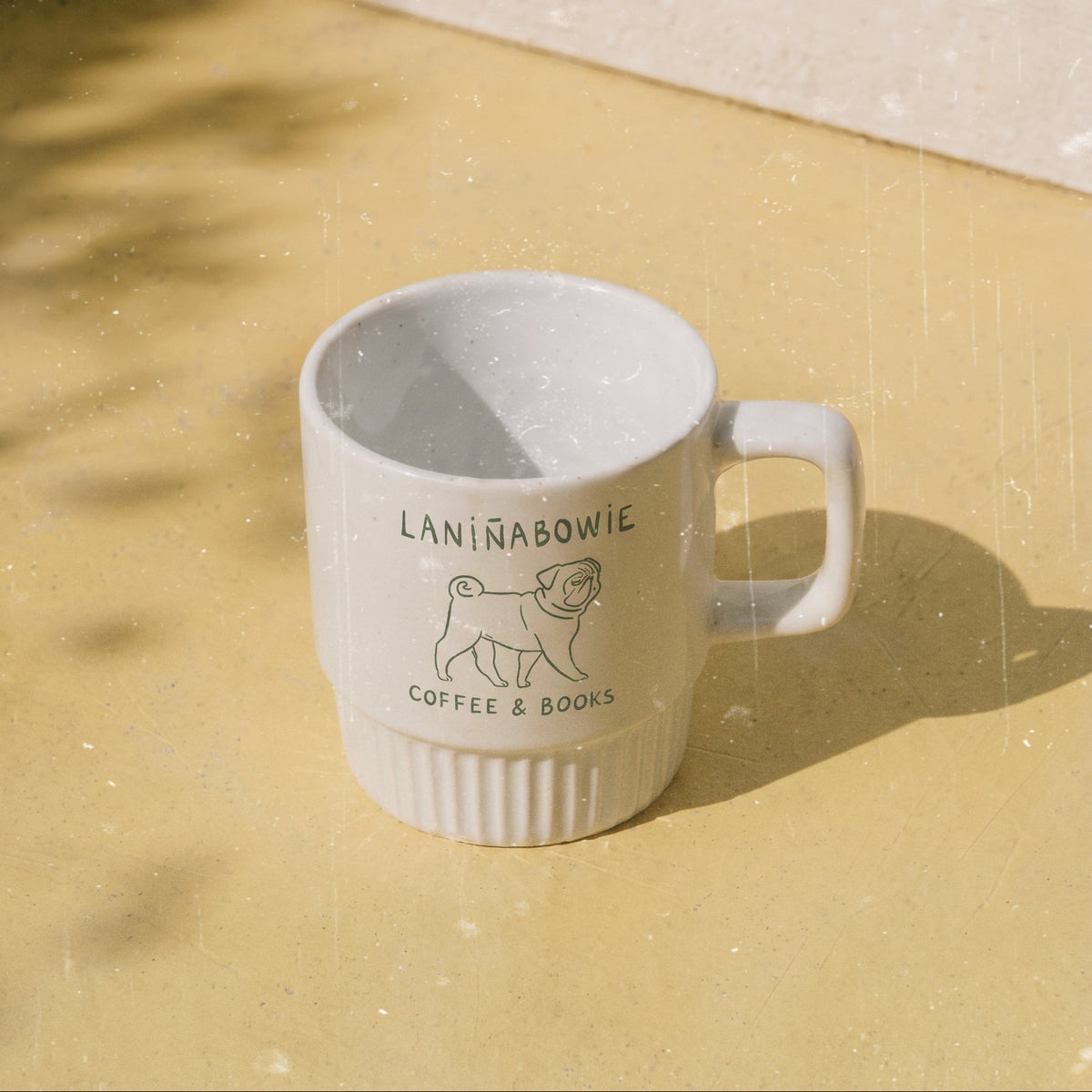Taza de cerámica de color blanco de Laniñabowie modelo "Laniñabowie café" con estampación hecho a mano en nuestro taller inspirada en los cafés típicos de algunos parques de ciudades como Londres que sirven café y puedes leer libros. Logo con perro pug. 