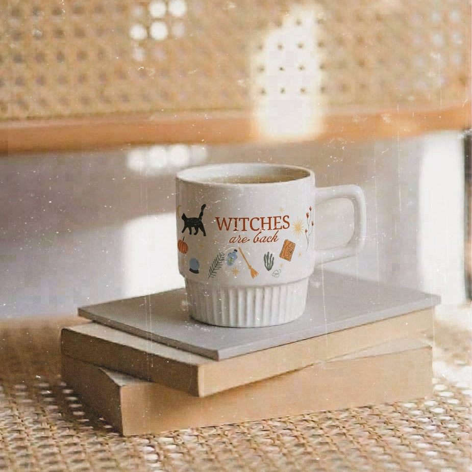 Taza de cerámica de color blanco de Laniñabowie modelo "Witches are back" con estampación hecho a mano en nuestro taller inspirada en el universo de Hocus Pocus con frase en rojo "witches are back" y elementos como el gato Binx. 