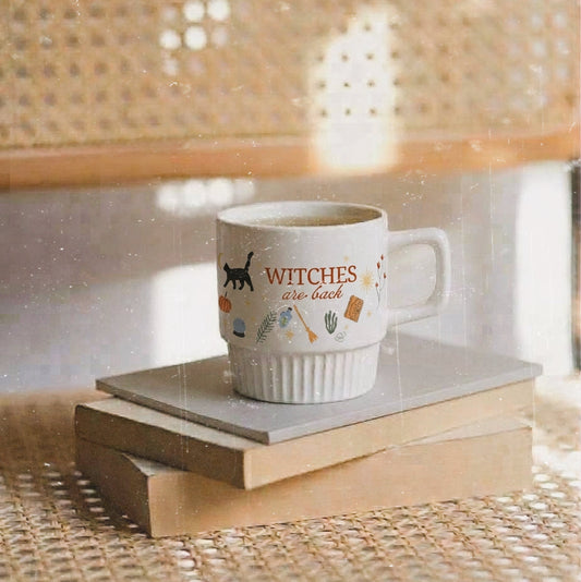 Taza de cerámica de color blanco de Laniñabowie modelo "Witches are back" con estampación hecho a mano en nuestro taller inspirada en el universo de Hocus Pocus con frase en rojo "witches are back" y elementos como el gato Binx. 